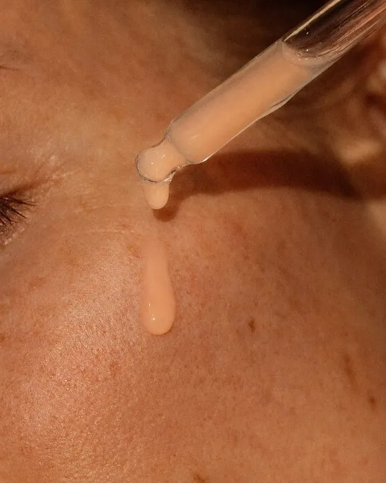 Detalhe do conta-gotas com sérum sobre a pele