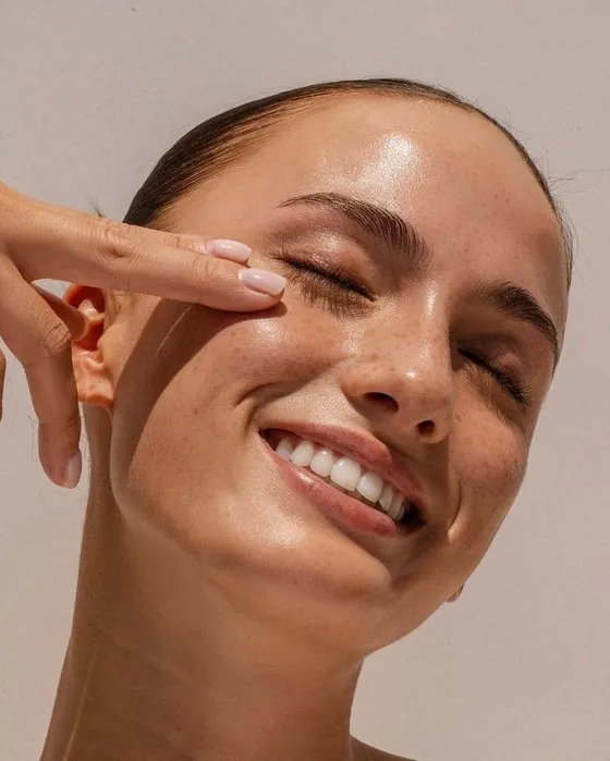 Mulher sorrindo aplicando sérum NanoGlow no rosto